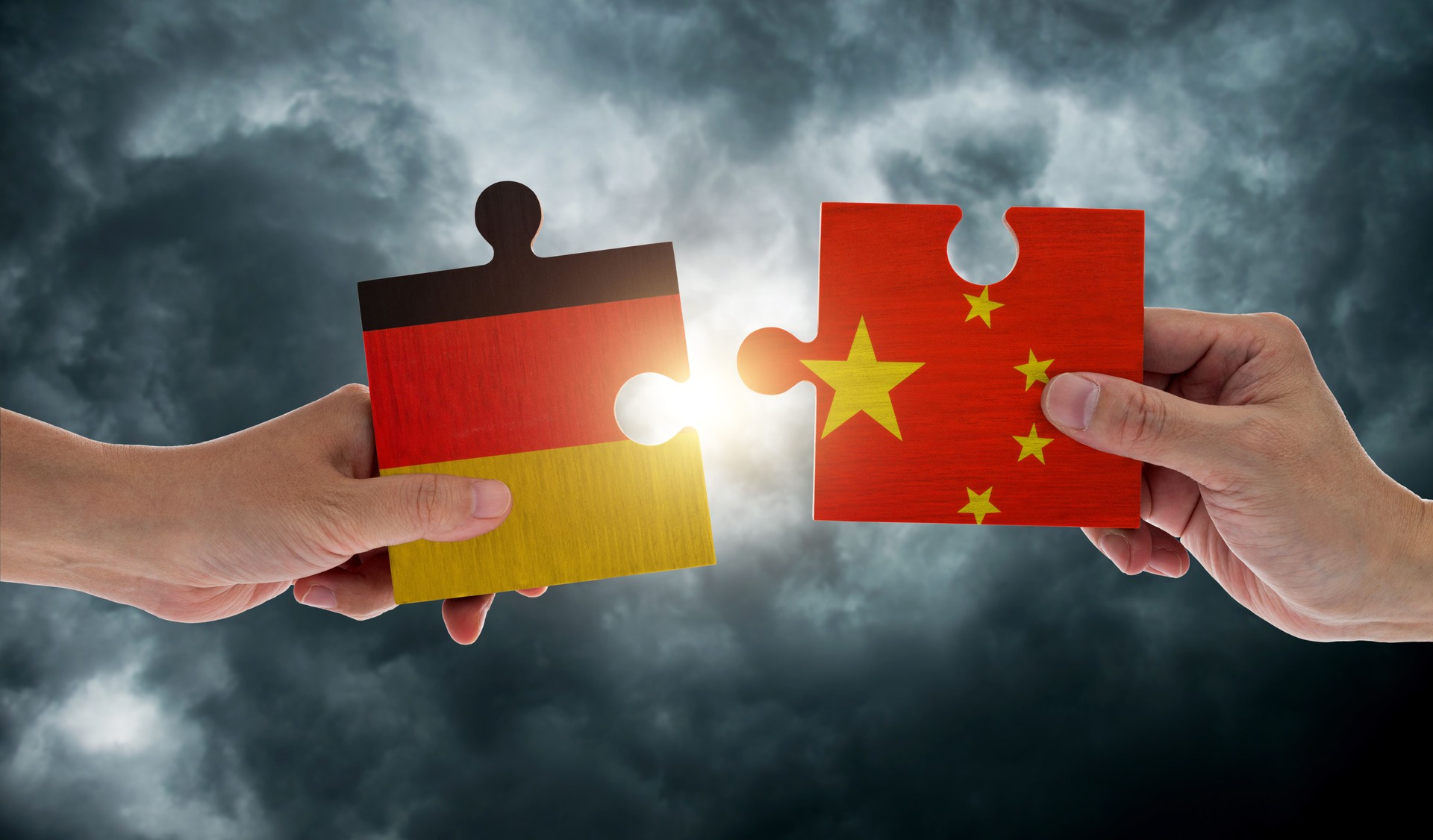 Hand holding Germany and China flags on puzzle pieces joining together